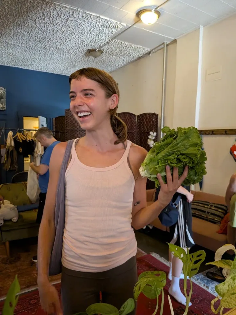 A guest at a summer pickup, smiling and holding a head of lettuce.